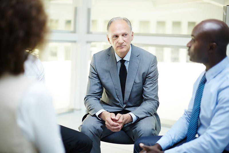 Attentive mature businessman listening to one of subordinates at