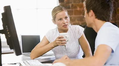 Two colleages have an engaged conversation over a hot beverage.