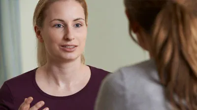 A woman has an engaged, active communication with another colleague.