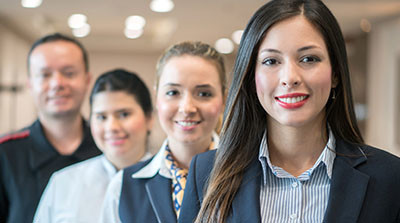 A diverse group of 4 colleague standing behind each other, smiling.