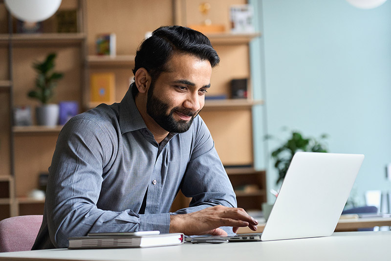 Smiling Indian Business Man Working On Laptop At Home Office. Yo